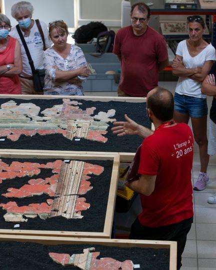 Toichographologue présentant le remontage des enduits peints dans le cadre de visites